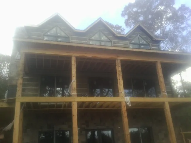 Dormers and porch framing on a large log home under construction — Roof Coating work by our crew in Lyman