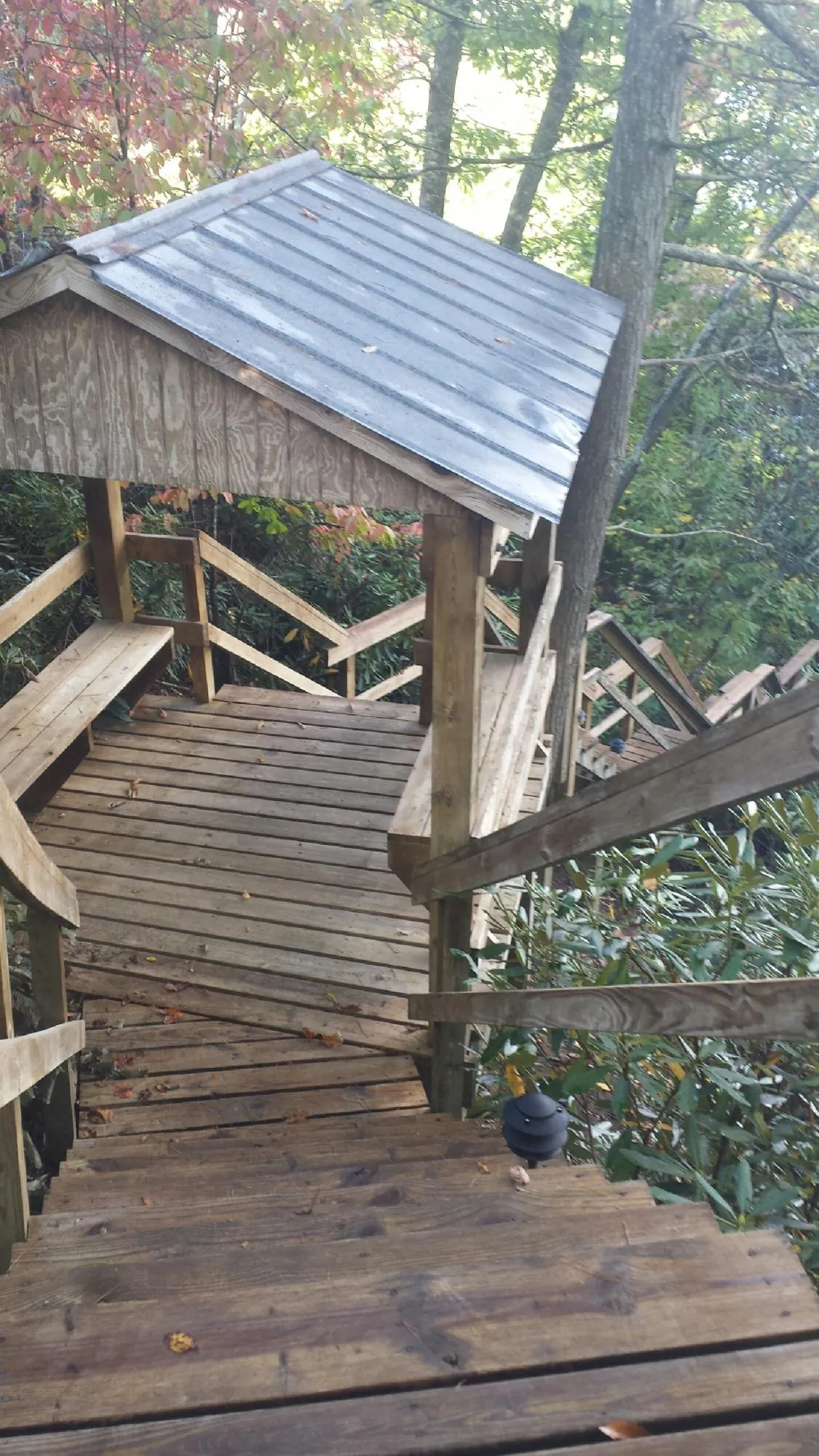 Metal roofed shelter over wooden steps on a wooded walkway — Skylight Repair & Installation work by our crew in Lyman