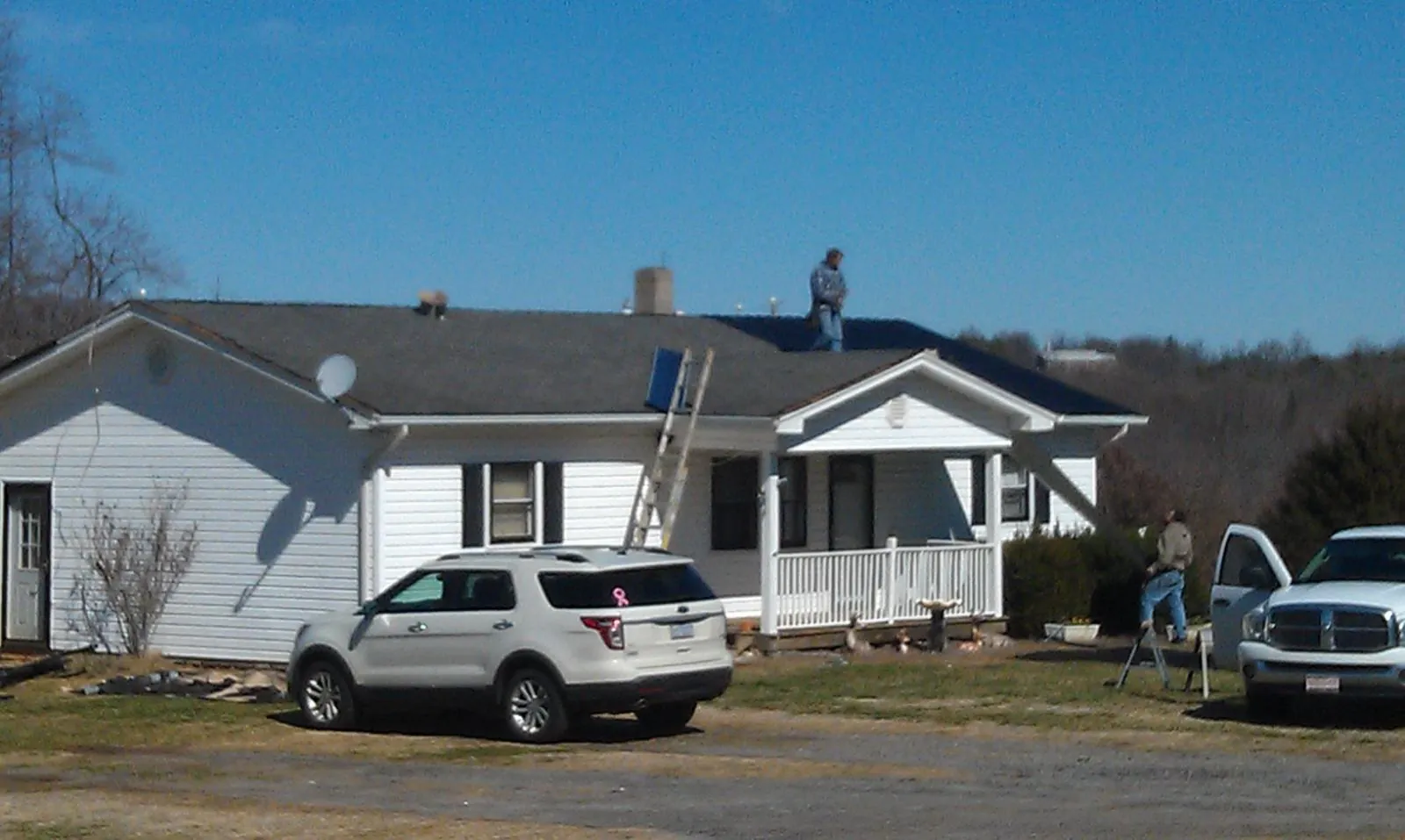 Roofers stripping shingles from a white ranch house roof in Lyman