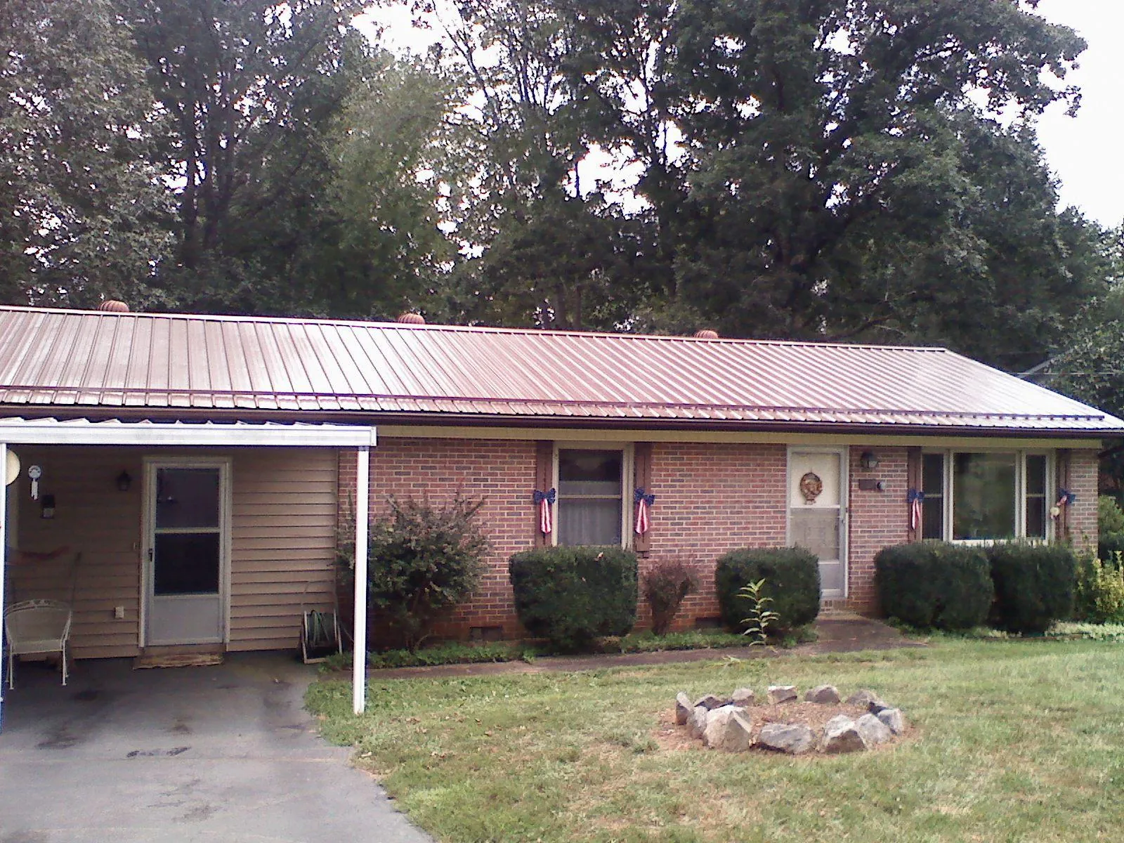Bronze metal roof and carport on a brick ranch home — Roof Repair work by our crew in Lyman